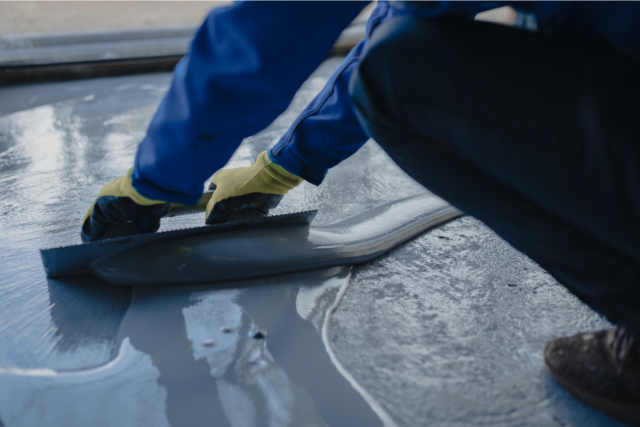 The worker applies gray epoxy resin to the new floor